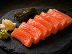 Kelp-cured premium salmon sashimi slices on dark slate with wasabi, pickled ginger and kombu kelp garnish, omakase fine dining