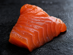 Macro close-up of kelp-cured salmon sashimi showing vibrant orange flesh and silky velvety texture on dark slate