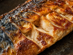 Macro close-up of grilled mackerel skin showing crispy golden-brown texture and glistening natural oils