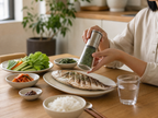 Korean dining table with gamtae sea salt grinder seasoning grilled fish dish, natural daylight home kitchen setting
