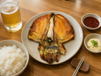 Korean casual table setting with grilled cuttlefish, steamed rice, chojang sauce, mayo and cold beer on bright wooden table