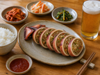 Korean casual table setting with squid sundae, steamed rice, dipping sauce and beer on bright wooden table